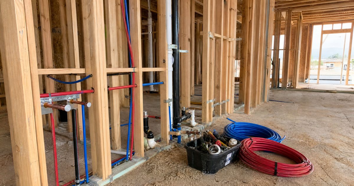 New construction plumbing rough-in with PEX water lines and ABS drain stacks inside a framed Hollister home