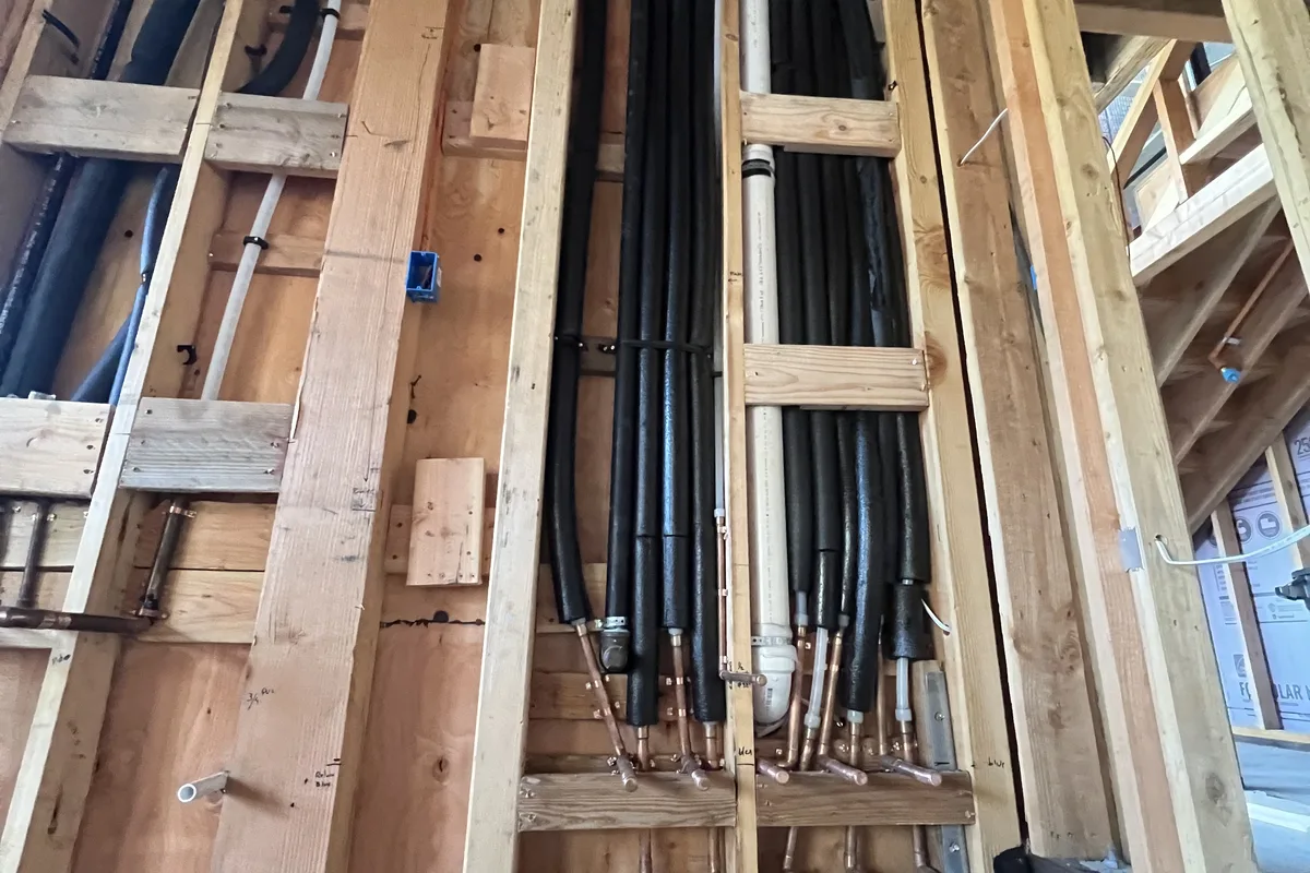 Relocated supply and drain-waste-vent lines run through open framing on a Hollister-area renovation.