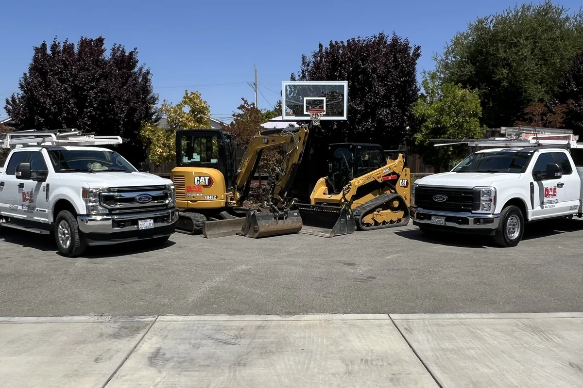 DAE Plumbing service trucks and excavation equipment staged for a ground-up construction project.
