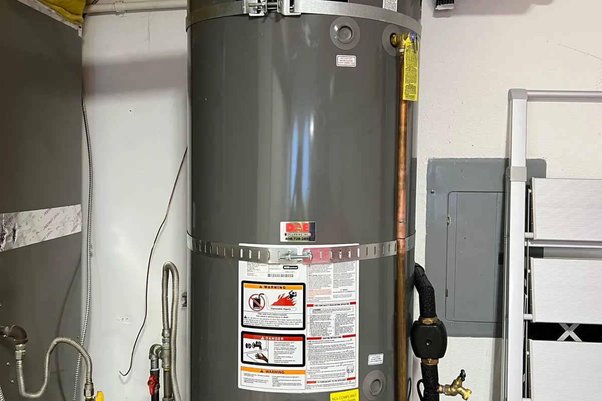 Large-capacity gas water heater with seismic strapping, an expansion tank, and a recirculation pump.